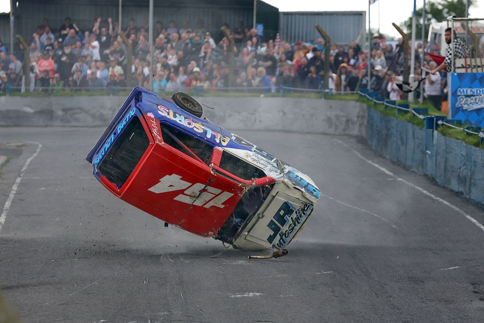 An upside down banger racing car landing on its driver's side headlight after toppling over and crashing